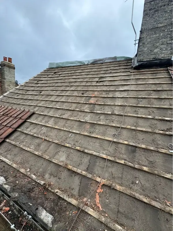 Roof tiles removed to expose the existing timber battens during a pitched roof replacement. By Norfolk Exterior Solutions.